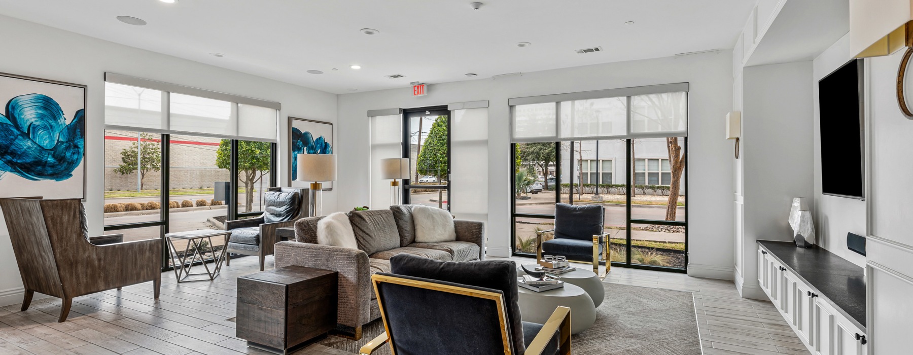 Modern resident lounge and business center with seating, tables, and TV at The Briscoe